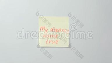特写女人`她的手贴着黄色的贴纸纸，上面写着我<strong>梦想成真</strong>的文字。